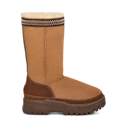 A brown suede-like tall UGG boot with a brown sole and patterned top.
