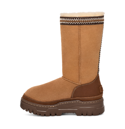 Tall, tan suede boot with a thick brown sole and a decorative zigzag pattern at the top.