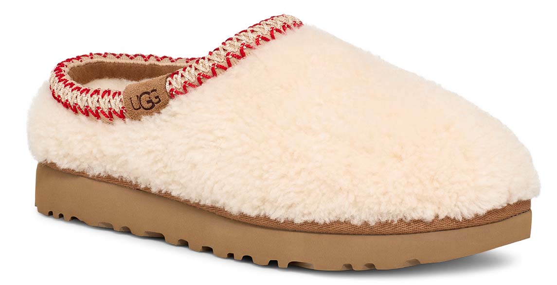 Slip-on house shoe with cream-colored plush upper, red and beige trim, tan sole and the letters UGG visible on the insole.