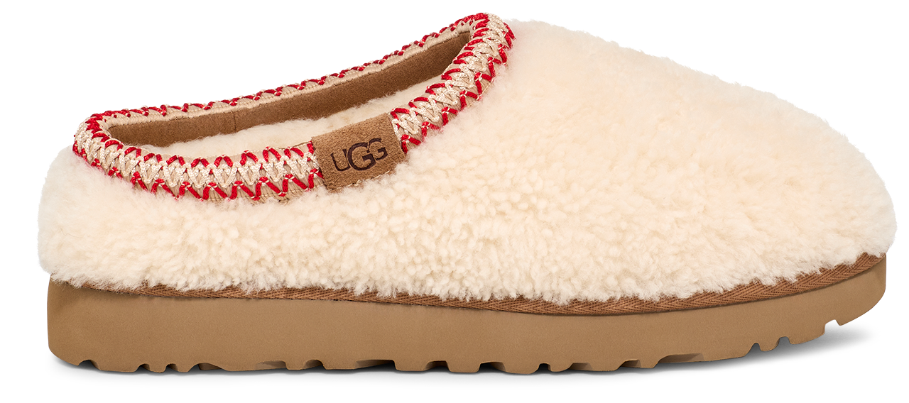 A white UGG slipper with red and white trim around the opening and a tan sole.