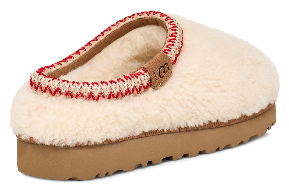 Slip-on slipper with off-white fleece upper, red and cream stitching around the collar, and a brown platform sole, showcasing a tan logo tag.