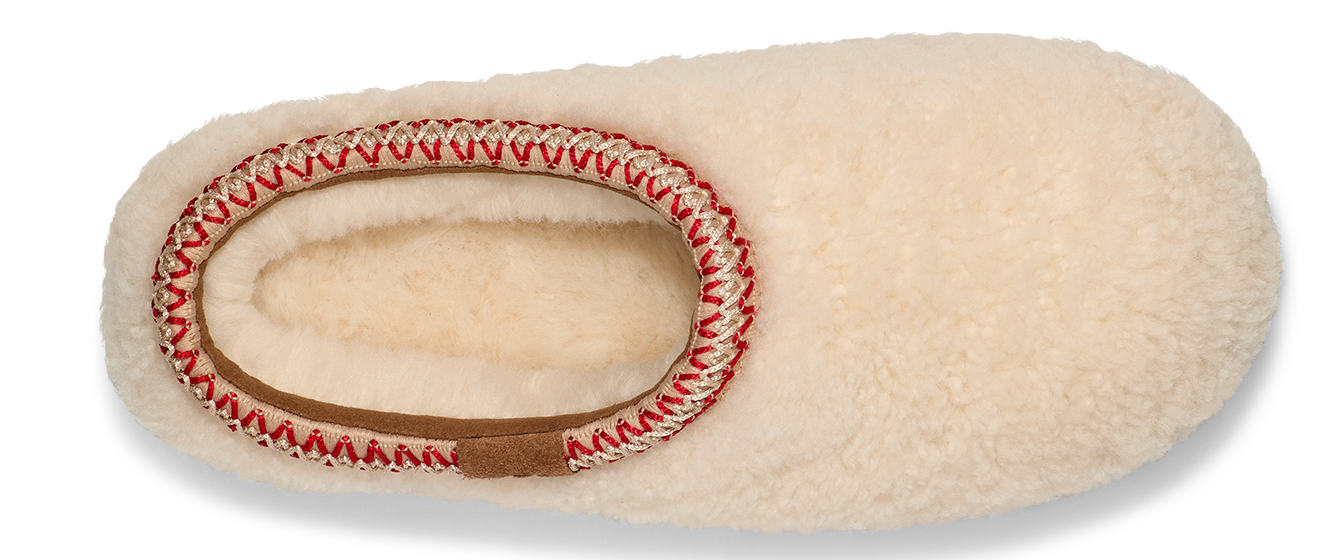 Cream colored, fuzzy slipper with red and tan trim around the foot opening.