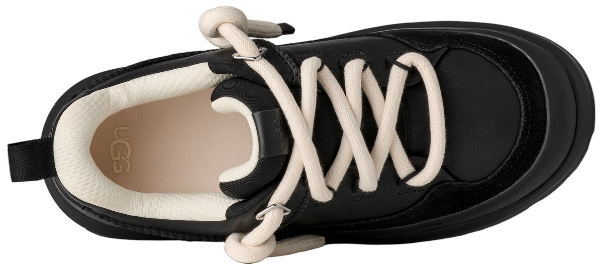 A top-down view of a black sneaker with a thick, off-white cord-style lace system, an off-white inner lining, and the brand name UGG printed on the insole.