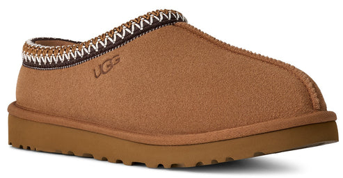 Slip-on brown slipper with white and brown decorative trim around the opening, and the letters UGG on the side.