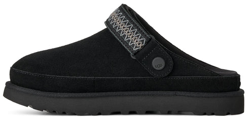 A black suede mule slip-on shoe with a thick sole and a decorative woven strap across the instep featuring a small circular branded button on the side.