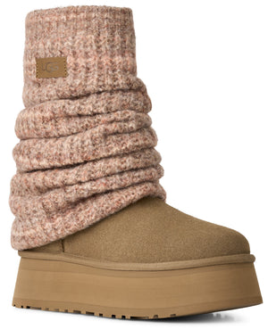 A tan suede platform boot featuring a tall, ribbed knit cuff in a soft, speckled dusty pink hue, with a small leather tag displaying UGG branding on the cuff.