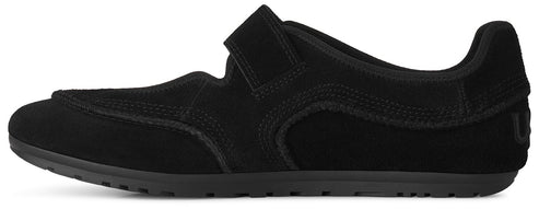 A black suede minimalist sneaker with a single Velcro strap over the instep and a thin, flat black rubber sole.