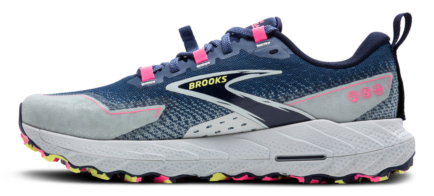 A side view of a trail running shoe with a navy and gray upper, pink accents, a white midsole, and a multicolored outsole.