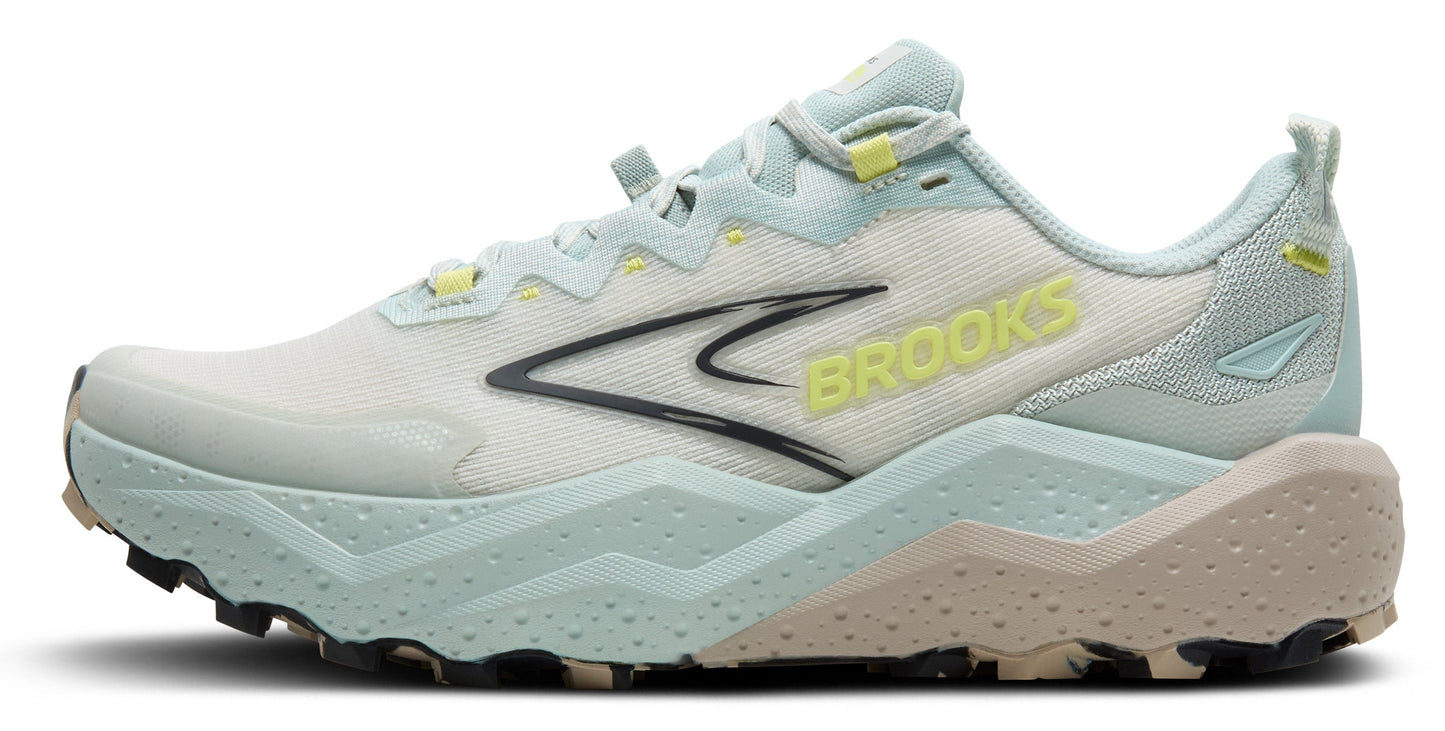 A side view of a light blue running shoe with a white mesh upper, a black logo, yellow text that reads "BROOKS" on the side, and a brown textured sole.