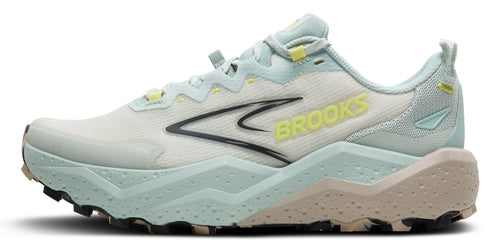 A side view of a light blue running shoe with a white mesh upper, a black logo, yellow text that reads "BROOKS" on the side, and a brown textured sole.