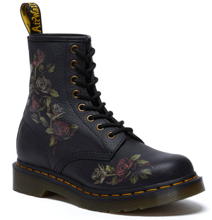 A black ankle boot with a yellow pull loop and floral print, laces, and yellow stitching along the sole.