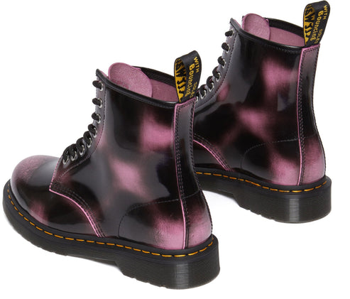 A pair of shiny boots with black laces and pink vapor-like patches.