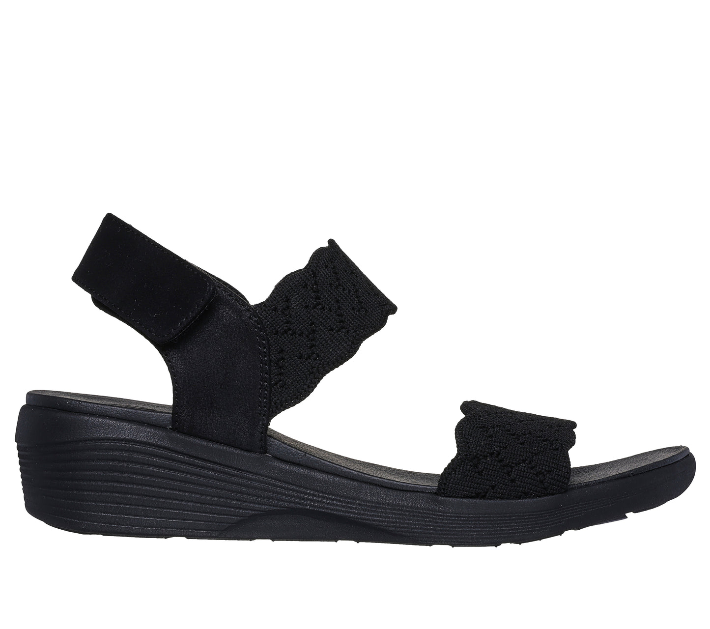 Black sandal with knitted elastic straps and a hook and loop closure.