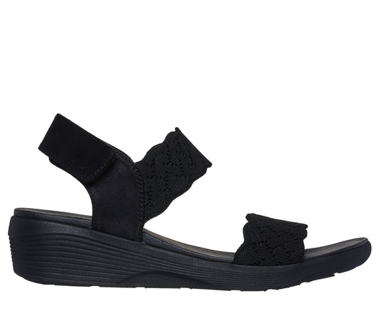 Black sandal with knitted elastic straps and a hook and loop closure.