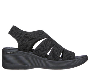 Black sandal featuring a wedge heel, peep toe, zigzag textured fabric, and elasticized slingback strap.