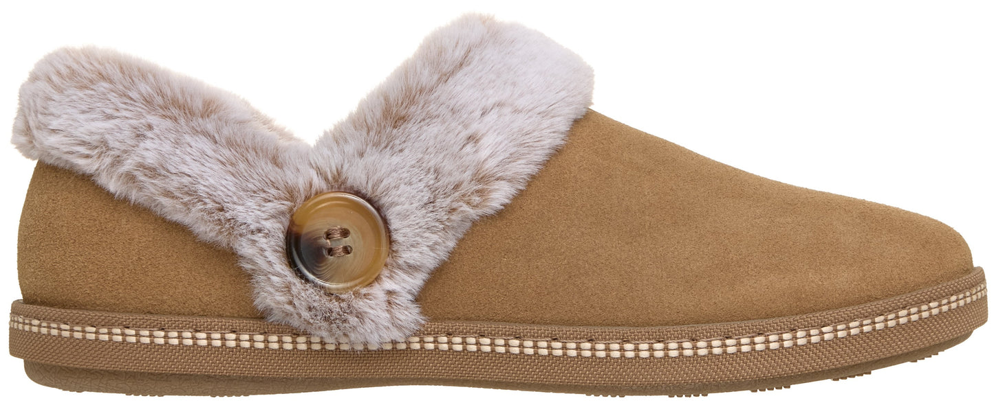 A tan suede-like slipper with a light gray faux fur collar and a single wooden-style button on the side, featuring visible stitching along the midsole.