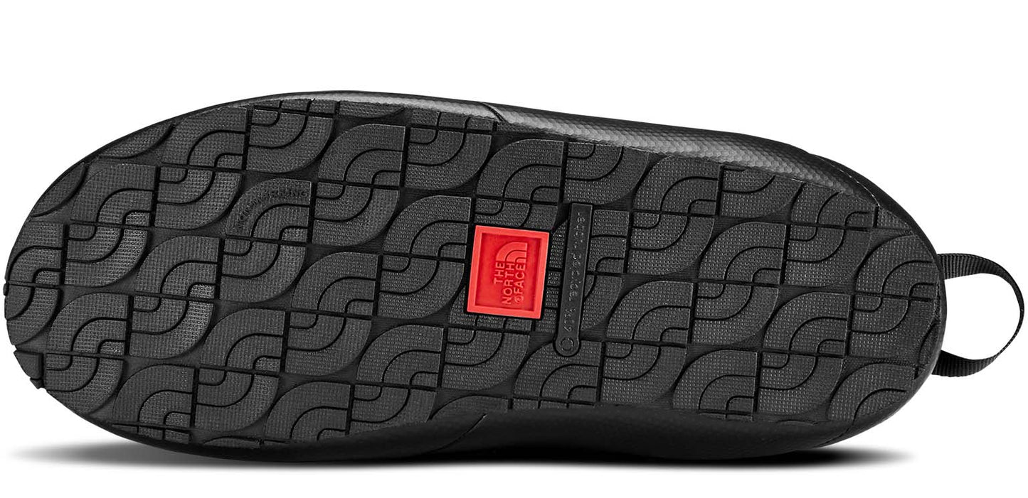 The bottom of a black shoe with a textured sole and a red square with a white logo.