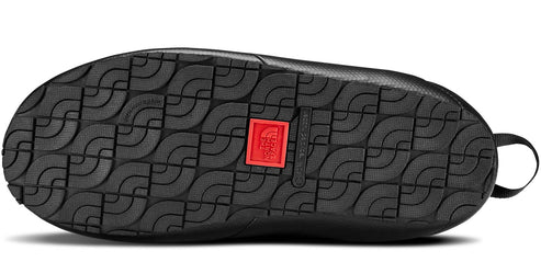 The bottom of a black shoe with a textured sole and a red square with a white logo.