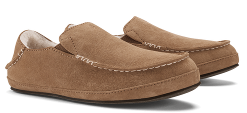 A pair of brown suede moccasin slippers with decorative stitching.