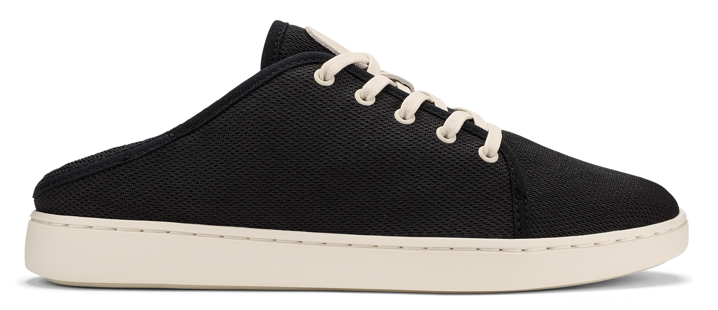 A slip-on sneaker featuring black canvas and white laces.