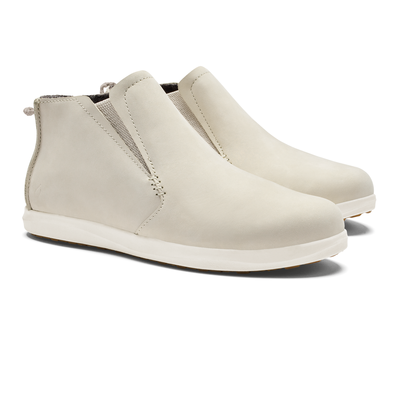 A pair of slip-on, off-white ankle boots with elastic side panels, a rounded toe, and a flat white sole.