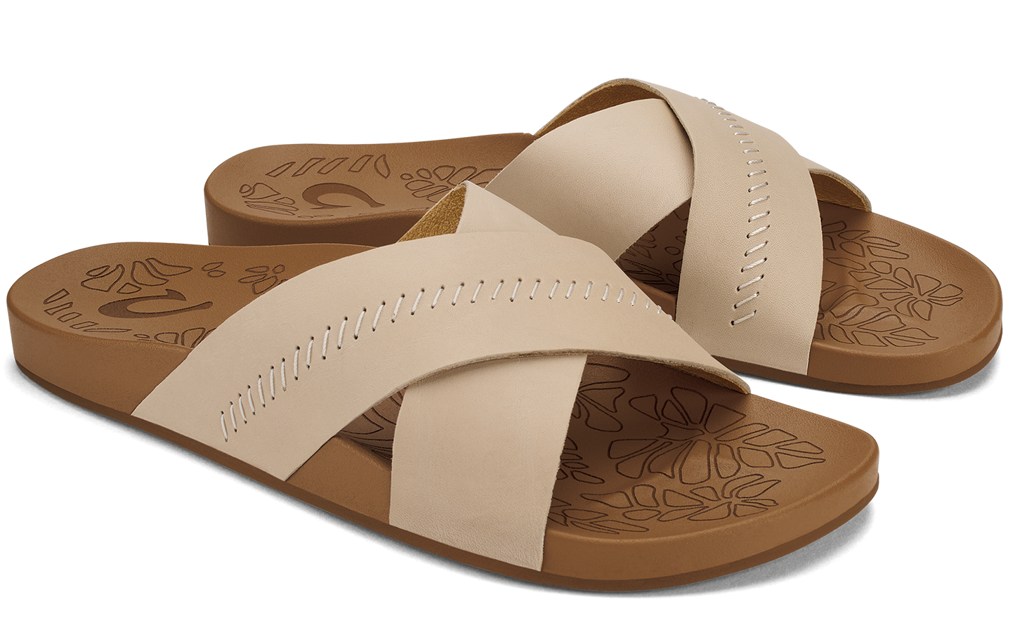 Pair of beige criss-cross strap slide sandals with brown soles.
