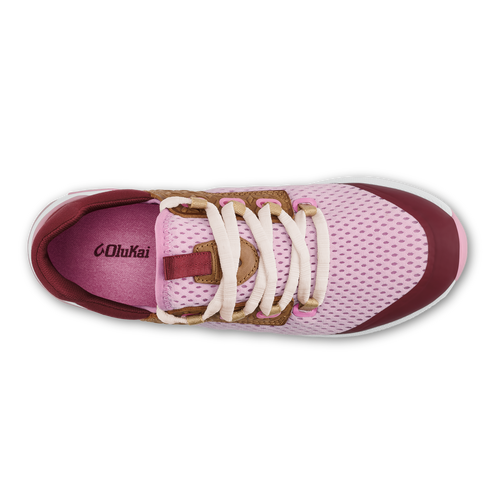 A top-down view of a light pink mesh sneaker featuring burgundy accents, off-white laces, and brown leather detailing, with the word OluKai visible on the purple insole.