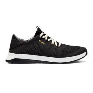 Black shoe with white laces and white midsole, with 'OluKai' in gold on side.