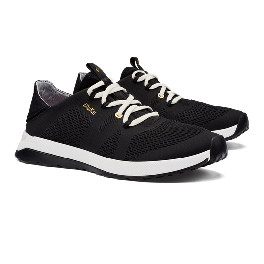 A pair of black running shoes with white laces and a white sole, with the word "OluKai" on the side.