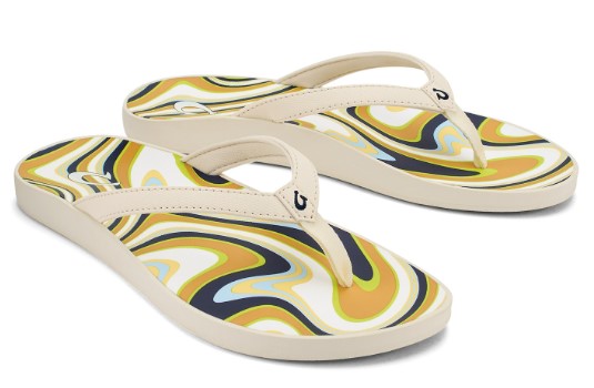 Pair of flip-flops with a cream strap and a wavy design footbed in tan, blue, and white.