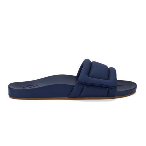 A side view of a navy blue slip-on sandal with a thick, padded strap across the top and a brown sole.