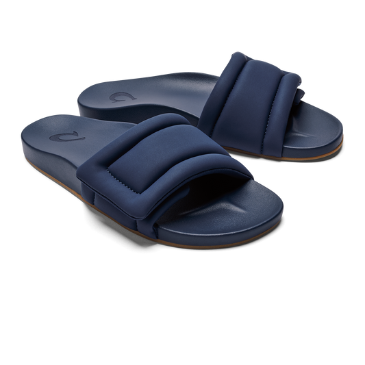 A pair of navy blue, wide-strap slides with a padded, rectangular design and a small embossed logo on the footbed.