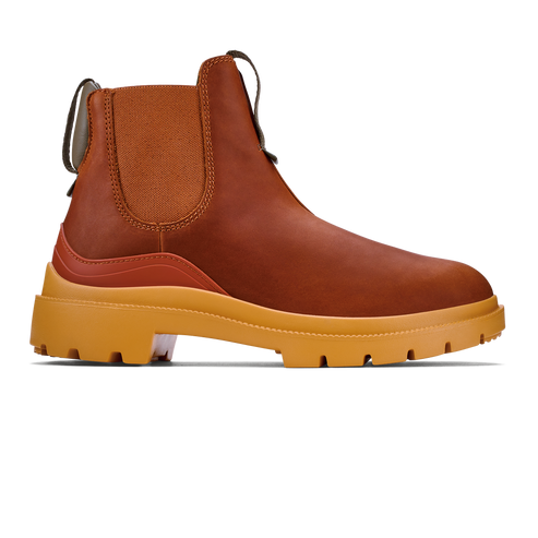 A brown Chelsea-style boot with a rugged, thick yellow lug sole and a matching textured elastic side panel, featuring a dark pull tab at the heel.
