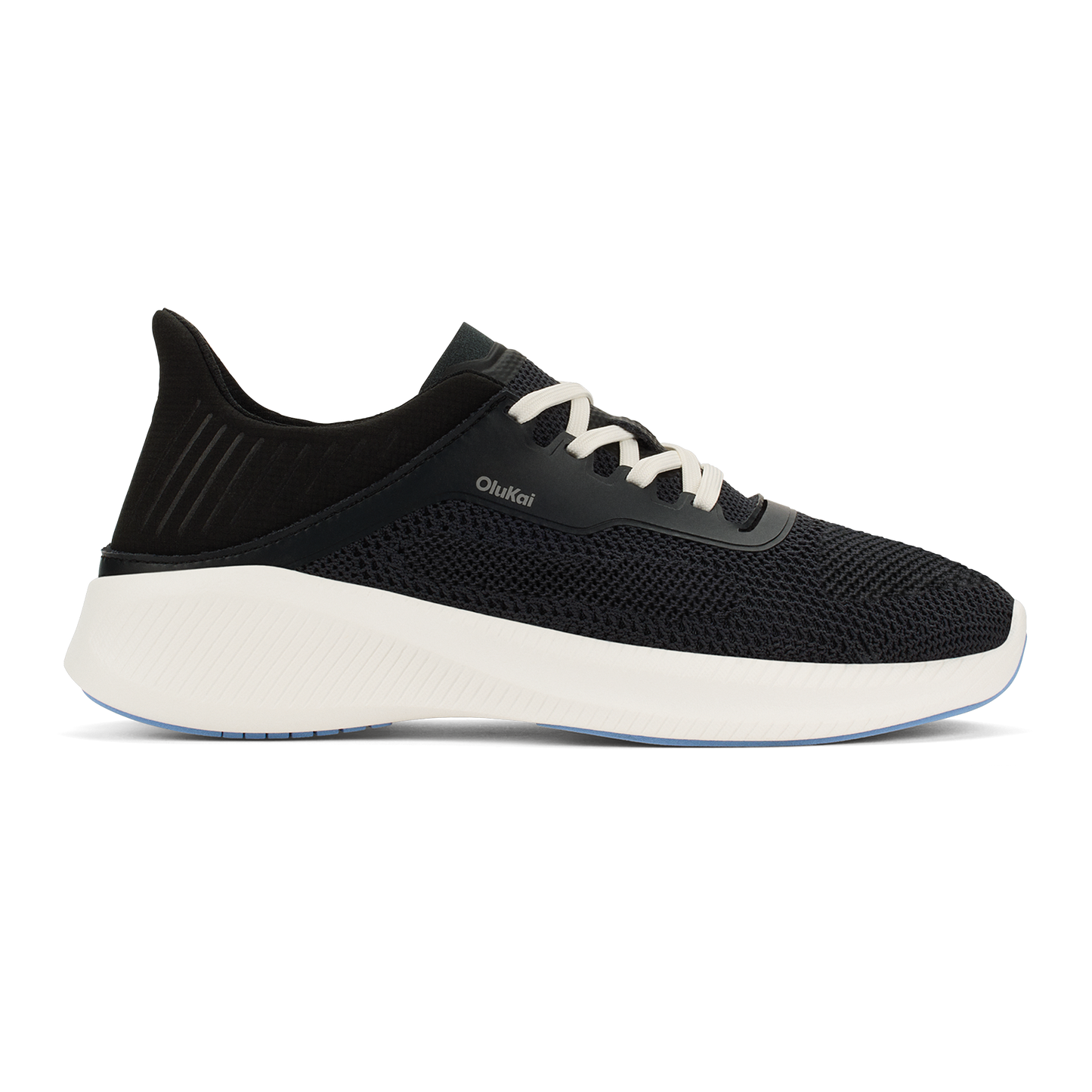 A black knit sneaker with white laces and a thick white foam sole, featuring a heel tab and the text OluKai on the side.