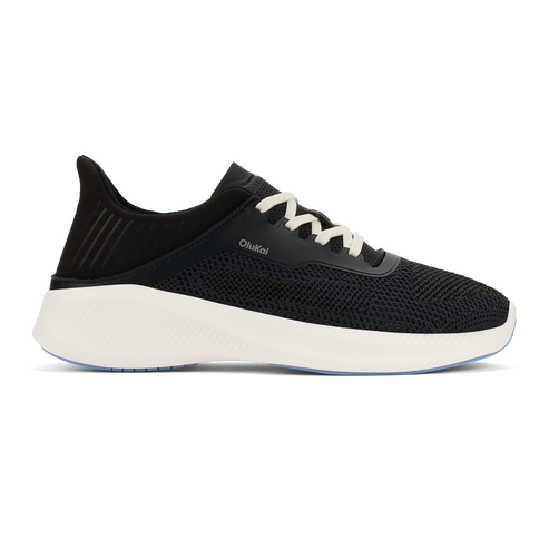 A black knit sneaker with white laces and a thick white foam sole, featuring a heel tab and the text OluKai on the side.