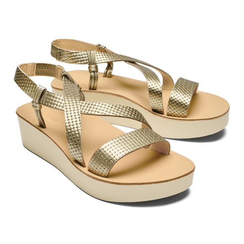 Pair of gold-colored platform sandals with crossover straps.