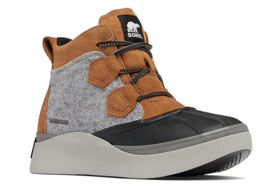 Ankle-high boot with a black rubber toe cap, tan suede upper with gray felt panel, black laces and a thick gray sole. The tongue has a square label with a white bear logo.