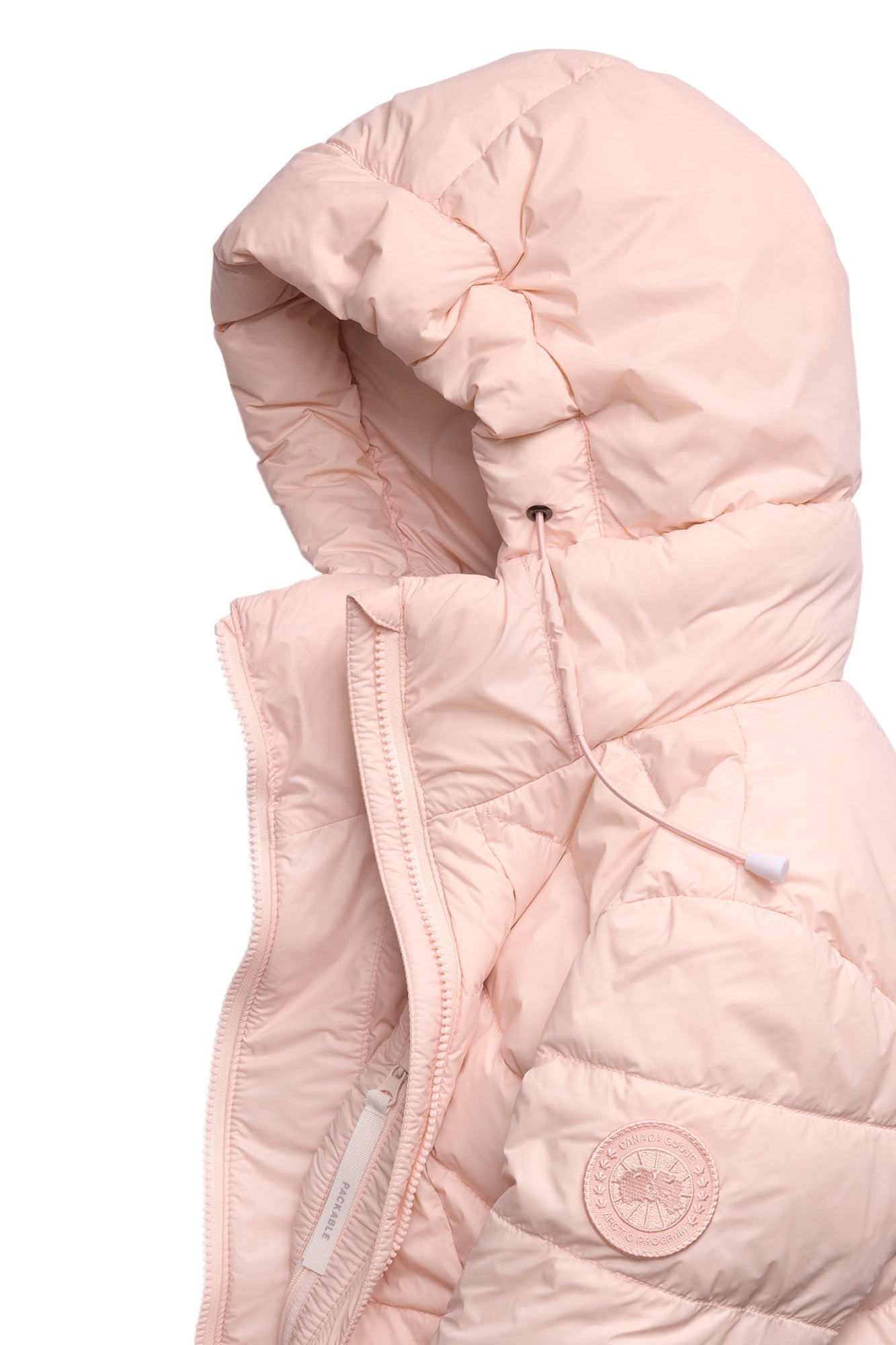 Close-up of a light pink puffer jacket with an attached hood and a circular emblem.