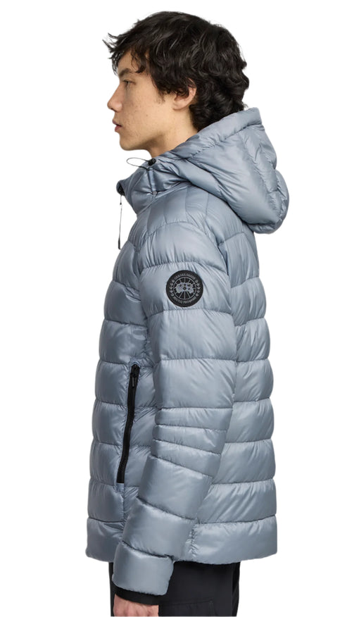 Side view of a light blue puffy jacket with a hood, black zipper, and emblem on the arm.