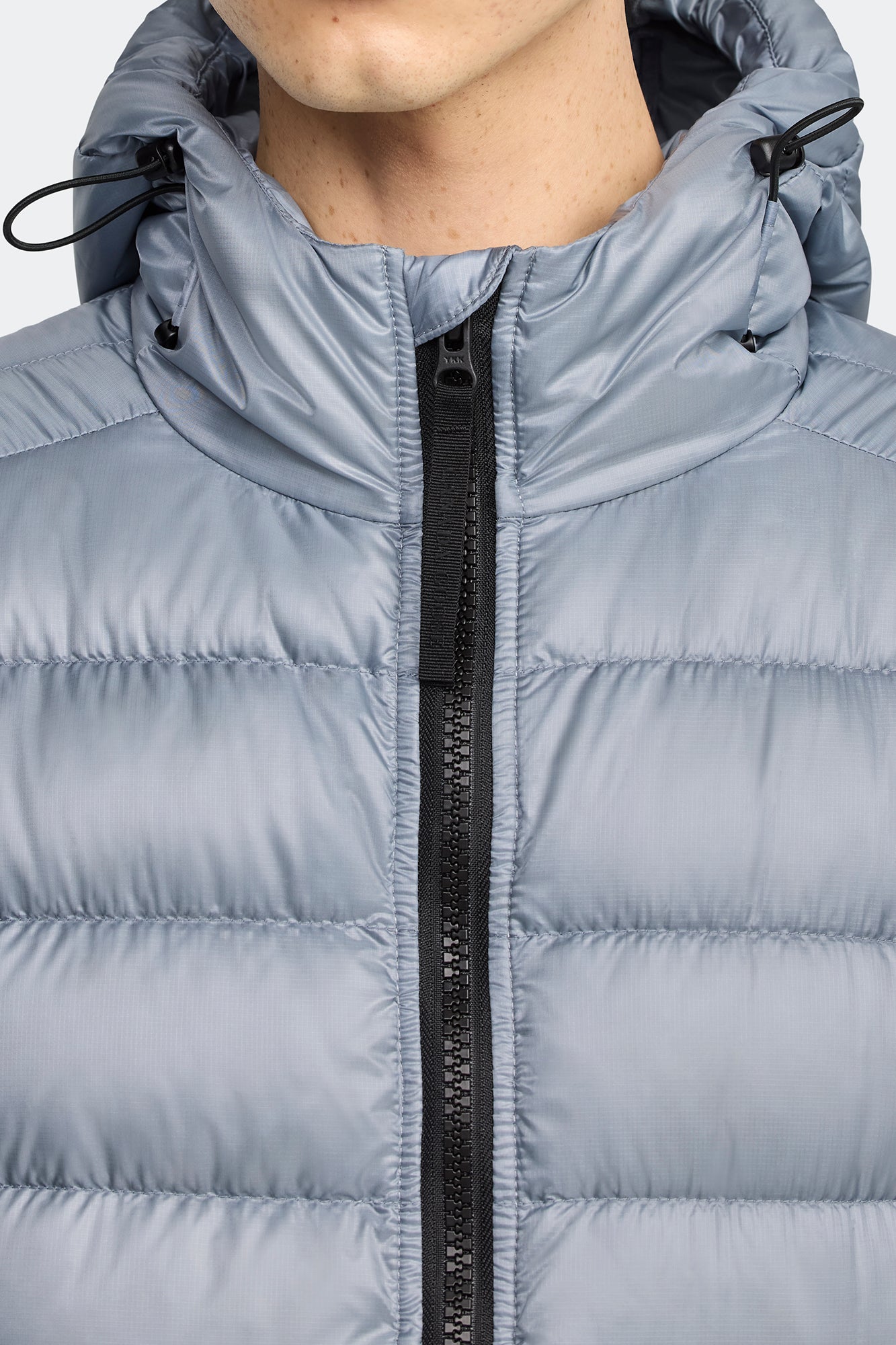 Close-up of a hooded gray puffer jacket with a black zipper.