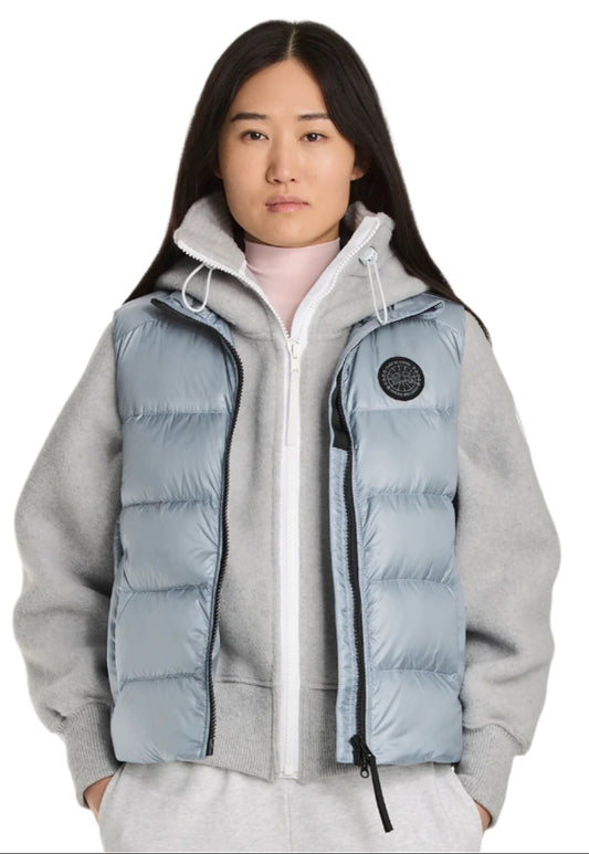 A person wearing a light gray puffer vest over a gray hooded sweatshirt.