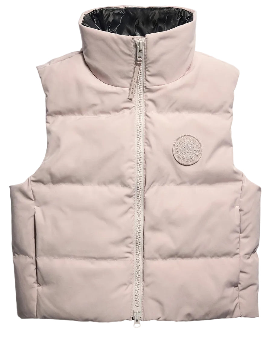 A light beige, sleeveless down puffer vest with a high collar, a central front zipper, and a circular patch logo on the upper left chest.