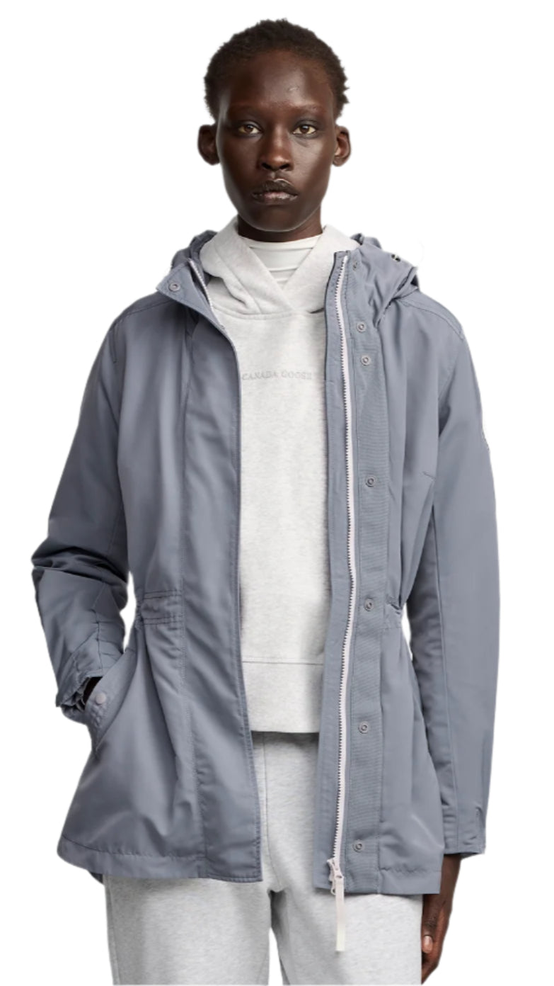 Person wearing a light-blue hooded lightweight jacket with zipper and buttons over a white top.