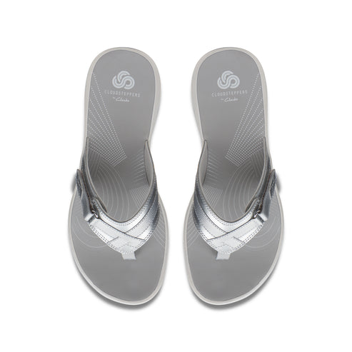 Two silver thong sandals with a silver strap and "Cloudsteppers by Clarks" printed on the insole.