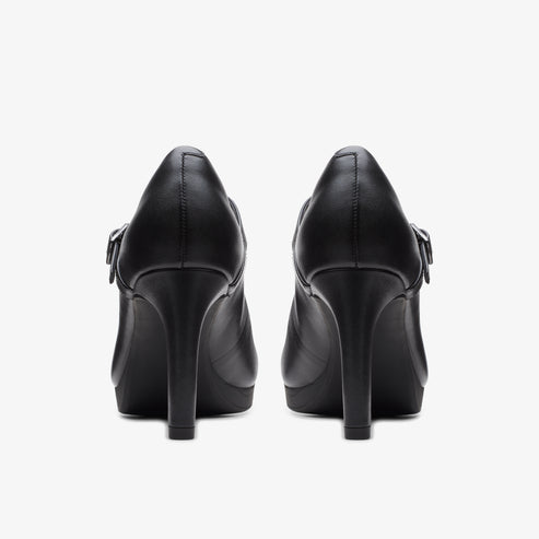 Pair of black leather high heel pumps with buckle strap, back view.