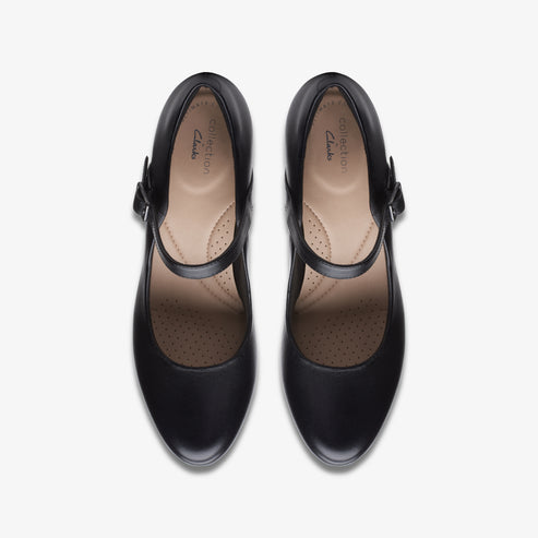 Overhead view of two identical black Mary Jane shoes with a strap, rounded toe, and a light-colored insole.
