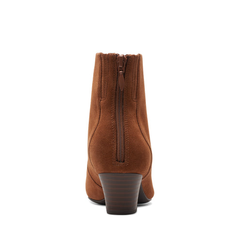 A back-facing view of an ankle-height, brown suede bootie with a chunky, stacked heel and a zipper closure at the back.