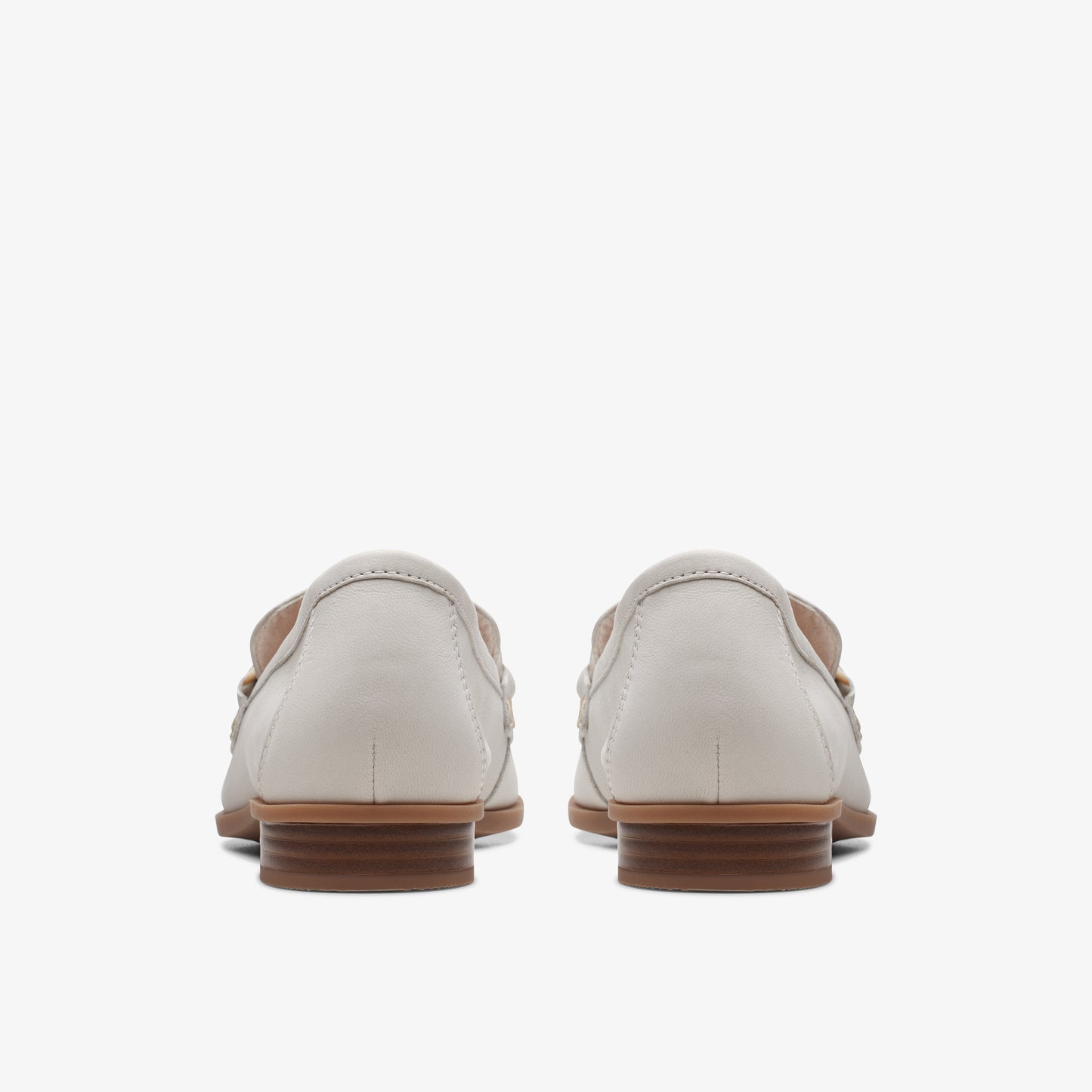 Pair of gray loafers with brown soles, seen from the back.