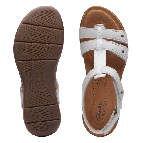 Pair of flat sandals, white straps with silver hardware, brown soles; one upside down showing tread.