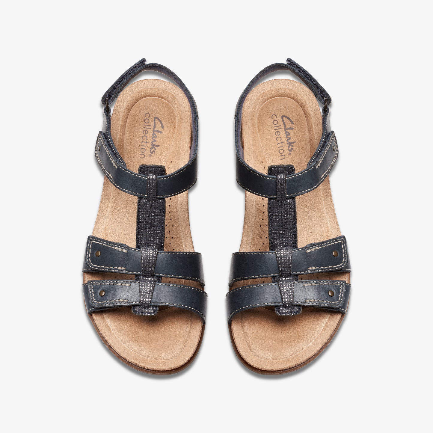 Overhead view of a pair of Clarks Collection black T-strap sandals with a tan footbed.